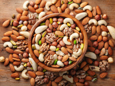 Wooden bowl with mixed nuts on rustic table top view. Healthy and nutrient food and snack.
